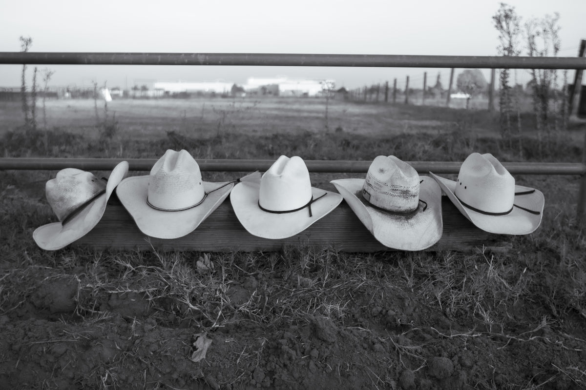 A row of cowboy hats sitting on top of a fence