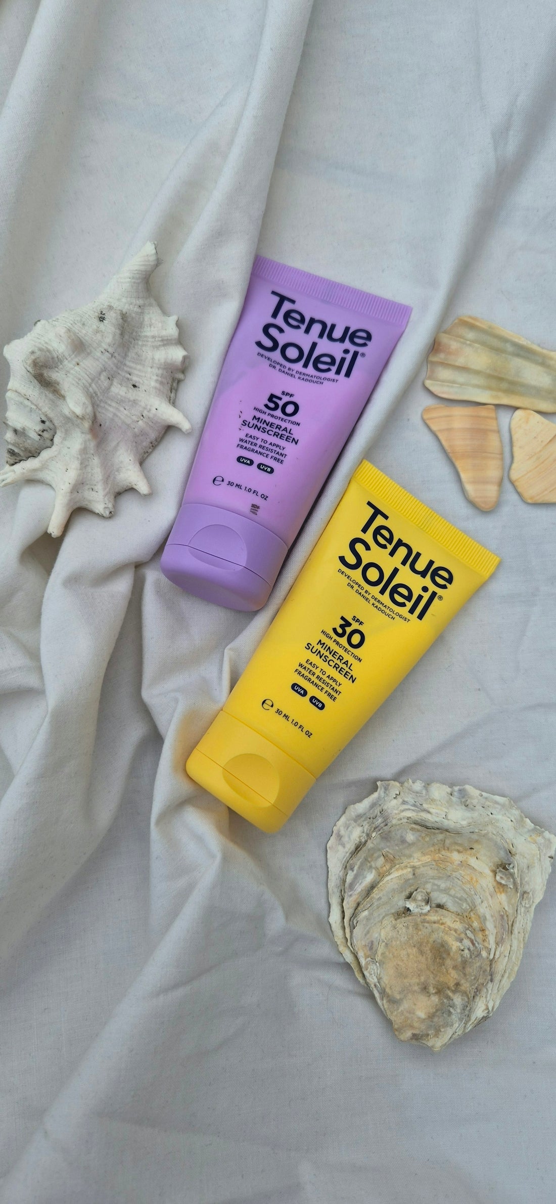 A bottle of sunscreen and a tube of sunscreen on a bed