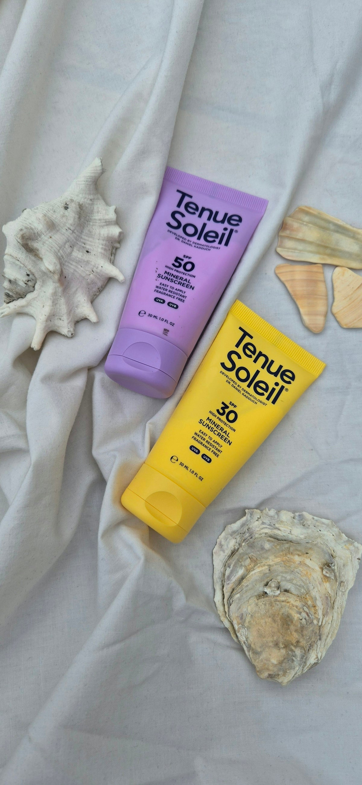 A bottle of sunscreen and a tube of sunscreen on a bed