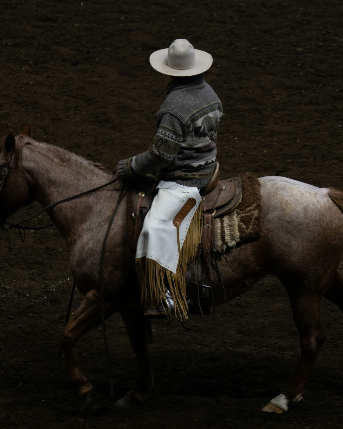A cowboy rides a horse in a rodeo arena.