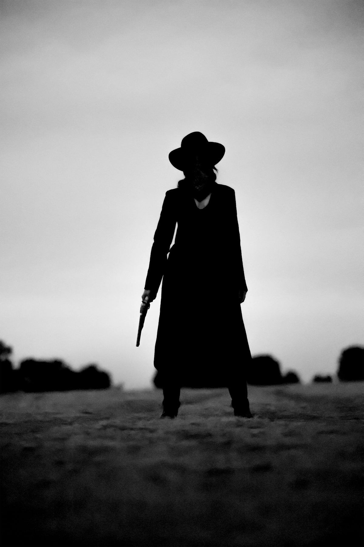 A western woman stands with a gun.