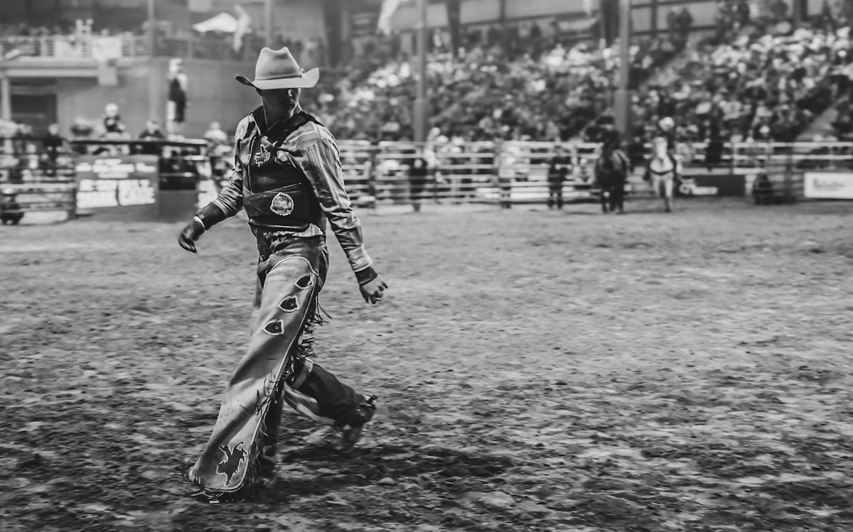 A cowboy walks after a rodeo event.