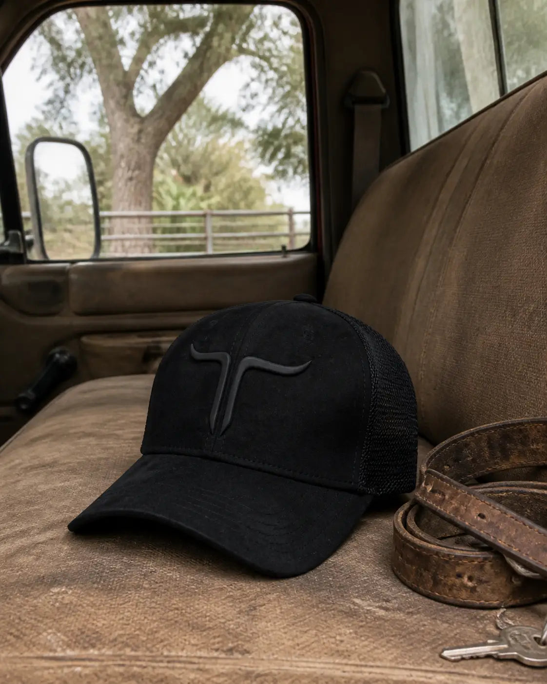 Black mesh-back ranch hat resting on the worn bench seat of a working pickup truck