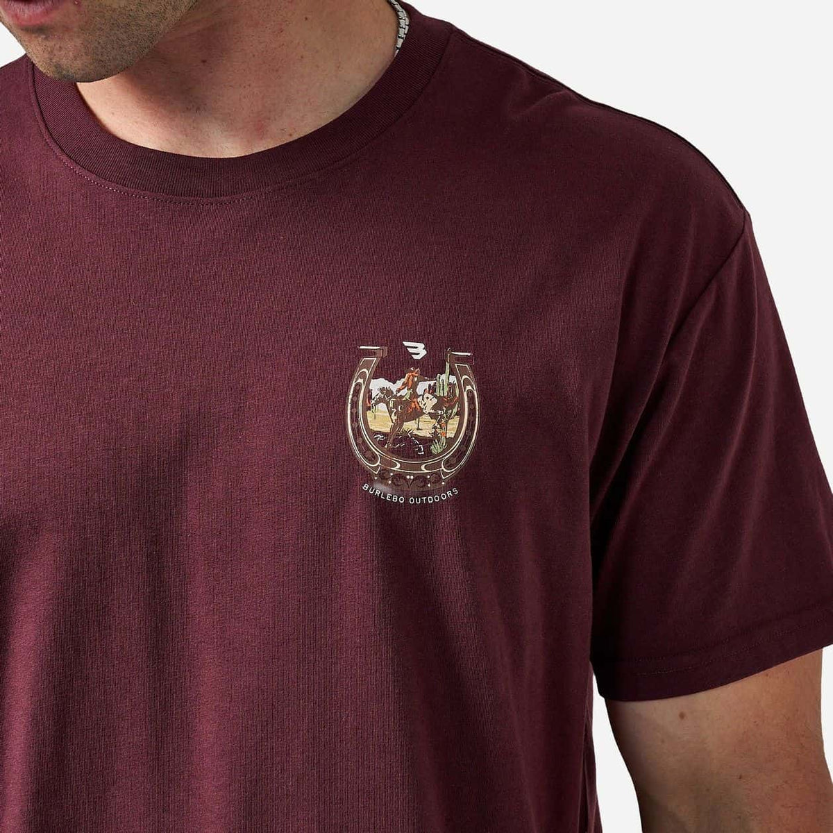 Close-up of horseshoe chest graphic on maroon tee