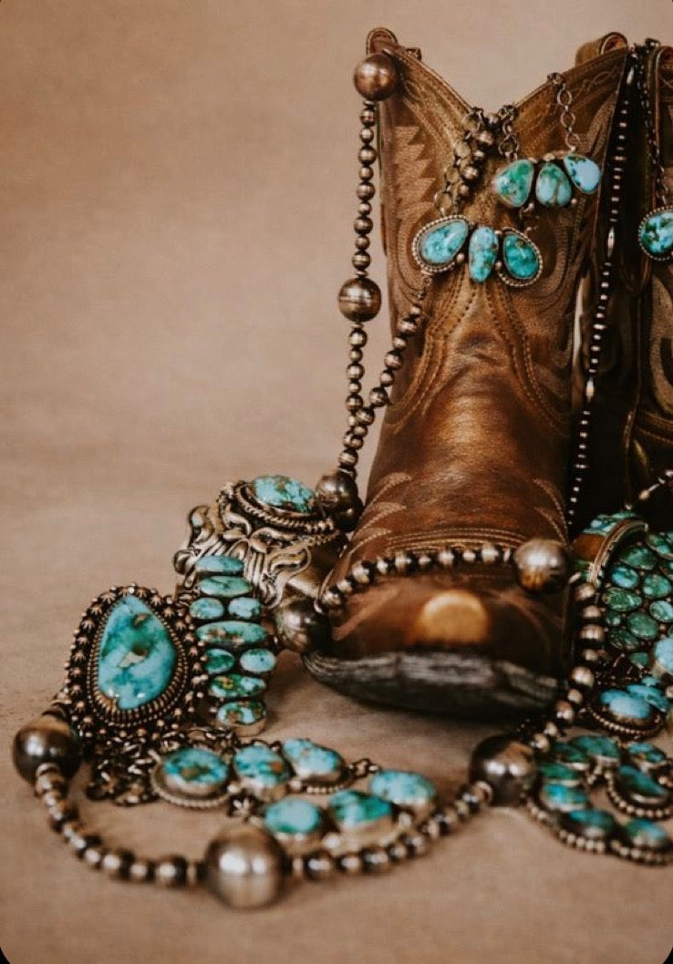 Turquoise jewelry arranged around worn western boots