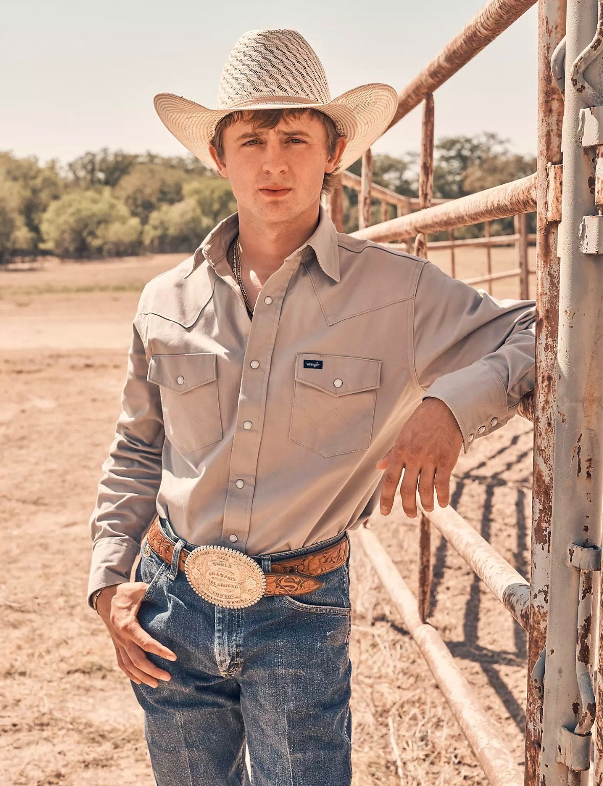 Cowboy in a western shirt and hat at a ranch gate